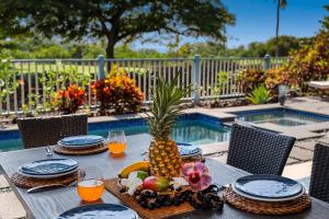 a table with a pineapple and fruit on it next to a pool at Kona Blue Vacations Holua Kai in Kailua-Kona