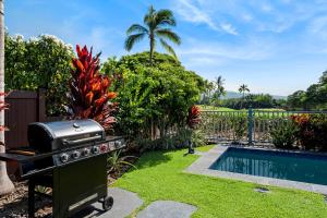 a barbecue grill in a yard next to a swimming pool at Kona Blue Vacations Holua Kai in Kailua-Kona