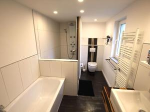 a white bathroom with a tub and a toilet at Holiday Home Weideblick by Interhome in Geestland