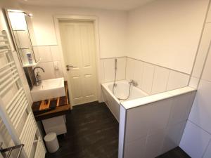 a white bathroom with a tub and a sink at Holiday Home Weideblick by Interhome in Geestland +17 photos