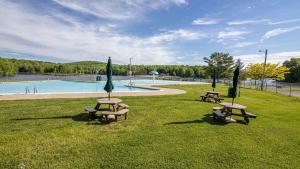 two picnic tables and umbrellas in a park with a pool at Chalet All Day by AvantStay in Arrowhead Lake
