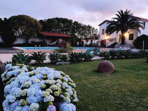 a garden with blue flowers in front of a house at La Finca de Ananás - House in Ponta Delgada