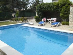 a swimming pool with a table and chairs next to it at Holiday Home Casa Blumer by Interhome in Les tres Cales