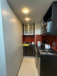 a small kitchen with black counter tops and cabinets at Urban II - Cómodo monoambiente en pleno centro in San Juan