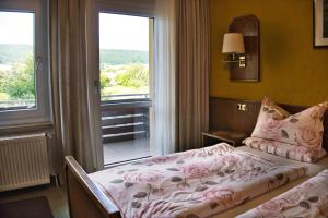 a bedroom with a bed with pink sheets and a window at Weigands Hotel Peter in Reinhardshagen +128 photos