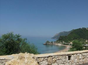 a view of a beach with a stone wall at Pool Apartments with panoramic Pelekas Beach view in Pelekas +14 photos