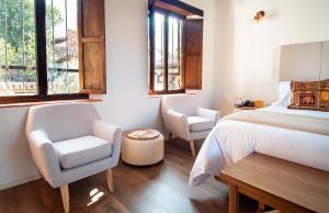 a bedroom with a bed and a chair and windows at Hotel Casa Alcestre in Villa de Leyva +82 photos