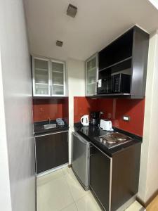 a small kitchen with stainless steel appliances and red walls at Urban III - Cómodo monoambiente en pleno centro in San Juan