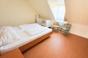 a bedroom with a bed and two chairs at Boddenhof Apartment 54 - Balkon, Parkplatz, ruhig in Stedar