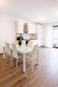a white dining room with a white table and chairs at Valtellinaresidence in Sondrio