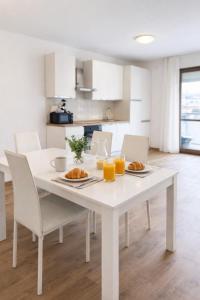 a white table with two plates of food and orange juice at Valtellinaresidence in Sondrio
