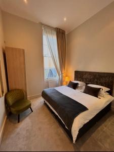 a bedroom with a bed and a chair and a window at Perfect In The Park in Glasgow