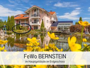 a house in the middle of a pond with yellow flowers at Apartment BERNSTEIN by Interhome in Wertach