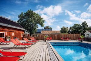 a swimming pool with red chairs and a fence at SleepCleeanGo L2 in Tofta