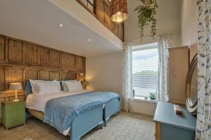 a bedroom with a blue bed and a window at Olive Orchard in Cropredy