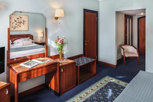 a bedroom with a desk and a bed and a mirror at Starhotels Du Parc in Parma