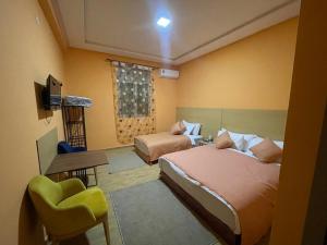 a bedroom with two beds and a chair and a television at Palm Garden in Erfoud