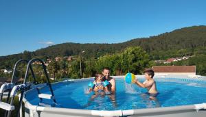 a man and two children playing with a frisbee in a swimming pool at Casa Santamaria a 5min de Noia cerca de la playa in Lousame