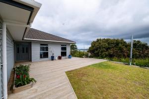 a backyard with a wooden deck and a house at Hook'em Heights in Pukenui