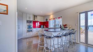 a kitchen with red cabinets and a bar with stools at Hook'em Heights in Pukenui