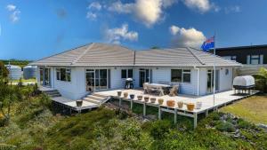 a white house with a deck with a picnic table at Hook'em Heights in Pukenui