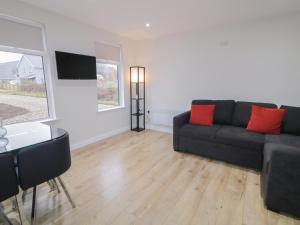 a living room with a black couch and a table at Binevenagh Point Cabin in Limavady