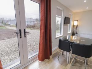 a dining room with a glass table and a window at Binevenagh Point Cabin in Limavady