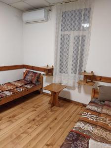 a room with two beds and a table and a window at Скай Румс -2 in Sofia