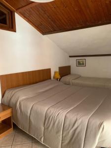 a bedroom with two beds and a wooden ceiling at Albergo Martinet in Vernante