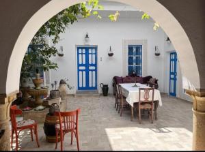 a dining room with blue doors and a table and chairs at Guesthouse DarHamdoun in Ḩammām al Ghazzāz