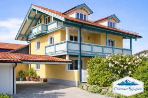 a yellow house with a red roof at ChiemseeRefugium - Ferienwohnung Park in Bernau am Chiemsee