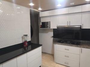 a kitchen with white cabinets and a black counter top at CRIMIg in Huamboya