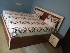 a bed with a wooden headboard and a night stand at El-Edu Villa in Oshien