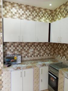 a kitchen with white cabinets and a tile wall at El-Edu Villa in Oshien