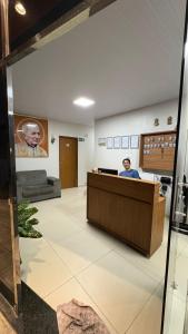 a man sitting at a reception desk in a waiting room at Pousada Rafael in Juazeiro do Norte