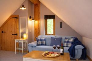 a living room with a blue couch and a table with wine glasses at Rowanlea Lodge Hot Tub Secure Garden Pub 5 min walk in Laurencekirk