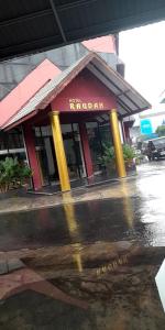 a building with a reflection in a puddle in the street at Hotel Raudah Kapuas in Kualakapuas