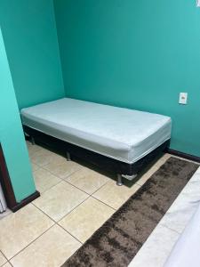 a bed in a room with a blue wall at Pousada Vitória in Iranduba