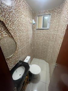 a bathroom with a toilet and a sink and a mirror at Apartamento Império das Marés in Paracuru +14 photos
