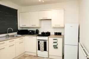 a kitchen with white cabinets and a white refrigerator at Contractor & Family Haven, Sleeps 7, Parking & Garden in Wednesfield