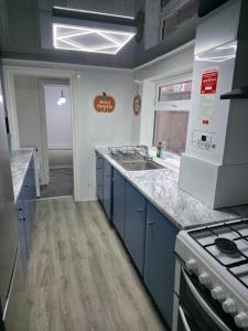 a kitchen with blue cabinets and a sink and a stove at Costa Home - 3 bed house with free on-street parking - ideal for workers in Middlesbrough +8 photos