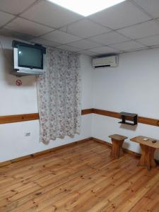 a room with a tv on the wall and a wooden floor at Скай Румс -3 in Sofia