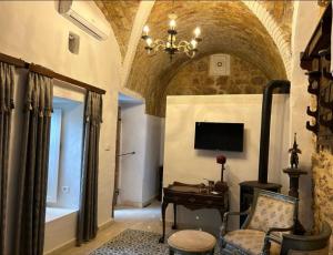 a living room with a tv and a chair and a desk at Guesthouse DarHamdoun in Ḩammām al Ghazzāz