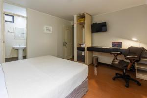 a bedroom with a bed and a desk and a chair at San Miguel Awanka Hotel in Lima