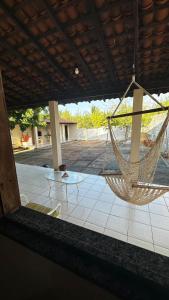 a hammock hanging from a patio with a table at Casas de Praia do Coqueiro com AR e varandas in Luis Correia