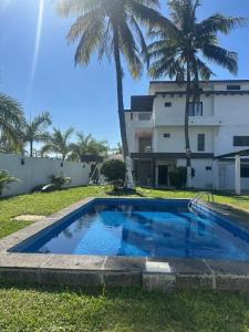 a swimming pool in front of a house with palm trees at Luxury loft with pool and beautiful view in Tampico