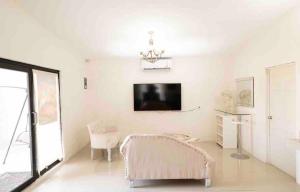 a white living room with a chair and a tv at Luxury loft with pool and beautiful view in Tampico