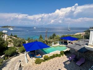 an aerial view of a swimming pool with blue umbrellas at Villa Avgerini Paxos in Gaios