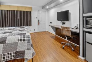 a bedroom with a bed and a desk and a television at 12 Oaks Hotel in Tyler
