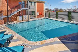 a swimming pool with blue chairs and a building at 12 Oaks Hotel in Tyler